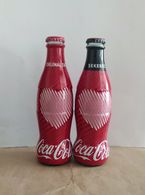 AC - COCA COLA HEARTH ILLUSTRATED SUGARLESS & ORIGINAL TASTE SHRINK WRAPPED 2 EMPTY GLASS BOTTLES & CROWN CAPSES & C - Flaschen