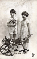 Enfants - Un Frère Et Une Sœur Posant Près D'une Brouette De Fleurs -  Carte Postale Ancienne - Gruppi Di Bambini & Famiglie