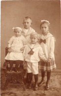 Carte Photo De Quatre Petit Enfant élégant Posant Dans Un Studio Photo Vers 1910 - Personnes Anonymes