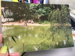 Snapshot Photo Couleur Homme, Femme, Accroupi, Au Bord De L’eau, Qui Regarde Un Hippopotame Dans Un Parc Dans Un Zoo - Personnes Anonymes