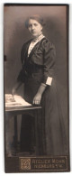 Fotografie Atelier Mohn, Nienburg A. W., Portrait Brünette Junge Schönheit Mit Zeitschrift Am Tisch Stehend  - Personnes Anonymes