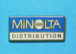 1 PIN'S  //   ** MINOLTA / DISTRIBUTION ** . (Arthus Bertrand Paris) - Informatica