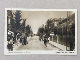 REAL PHOTO POSTCARD BY ELIAHU BROS - TEL AVIV, HERZL STREET AND THE GYMNASIUM. PALESTINE, ISRAEL - Palestina